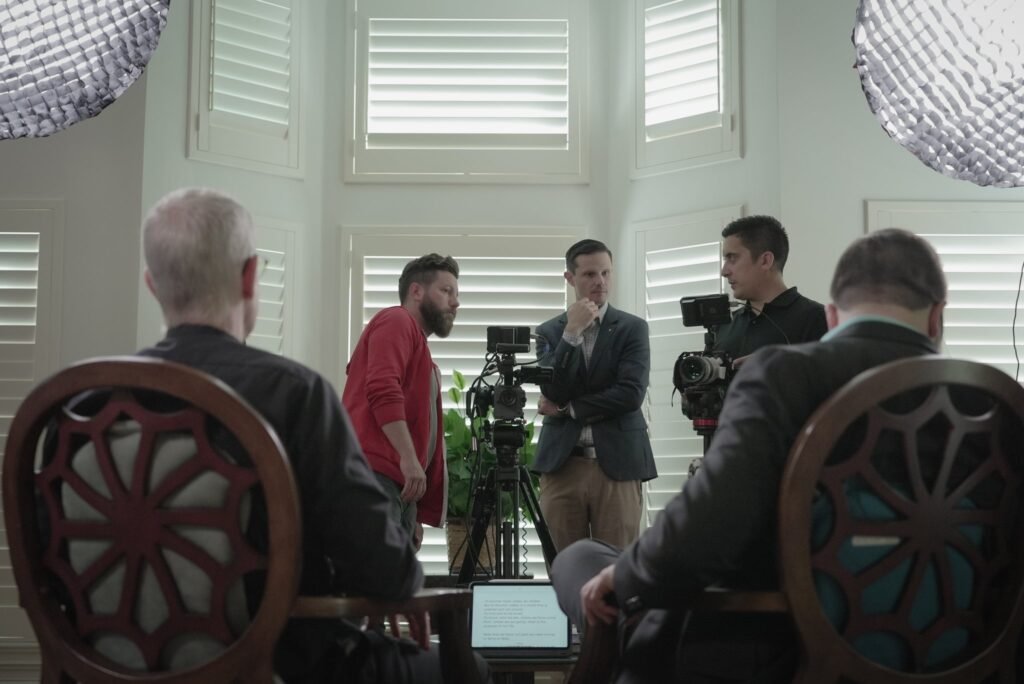 Adam Minihan speaking with the recording team alongside two colleagues during a podcast or interview recording session